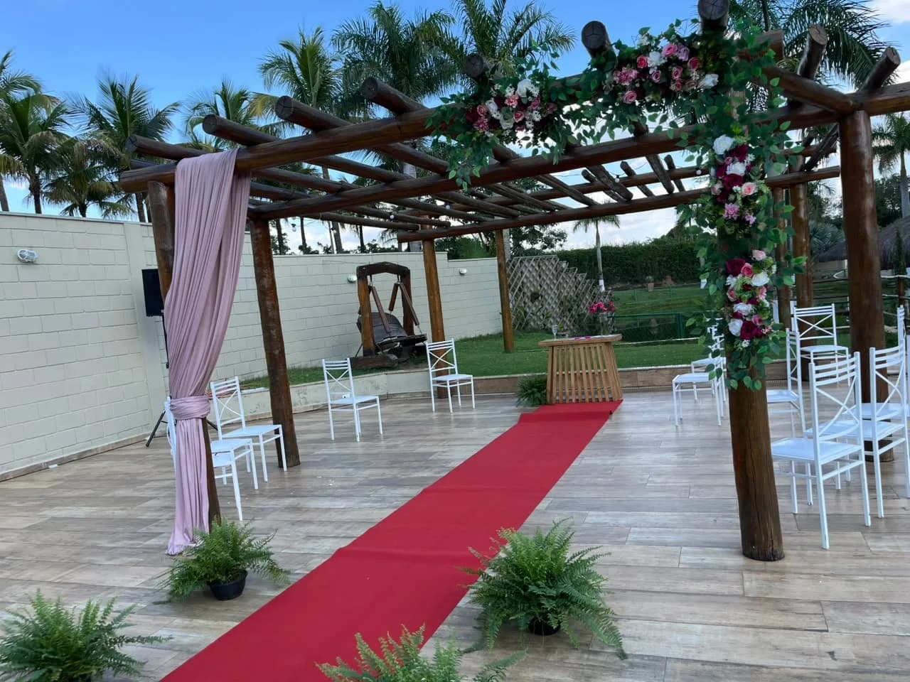 Altar em pergolado com flores e passadeira vermelha