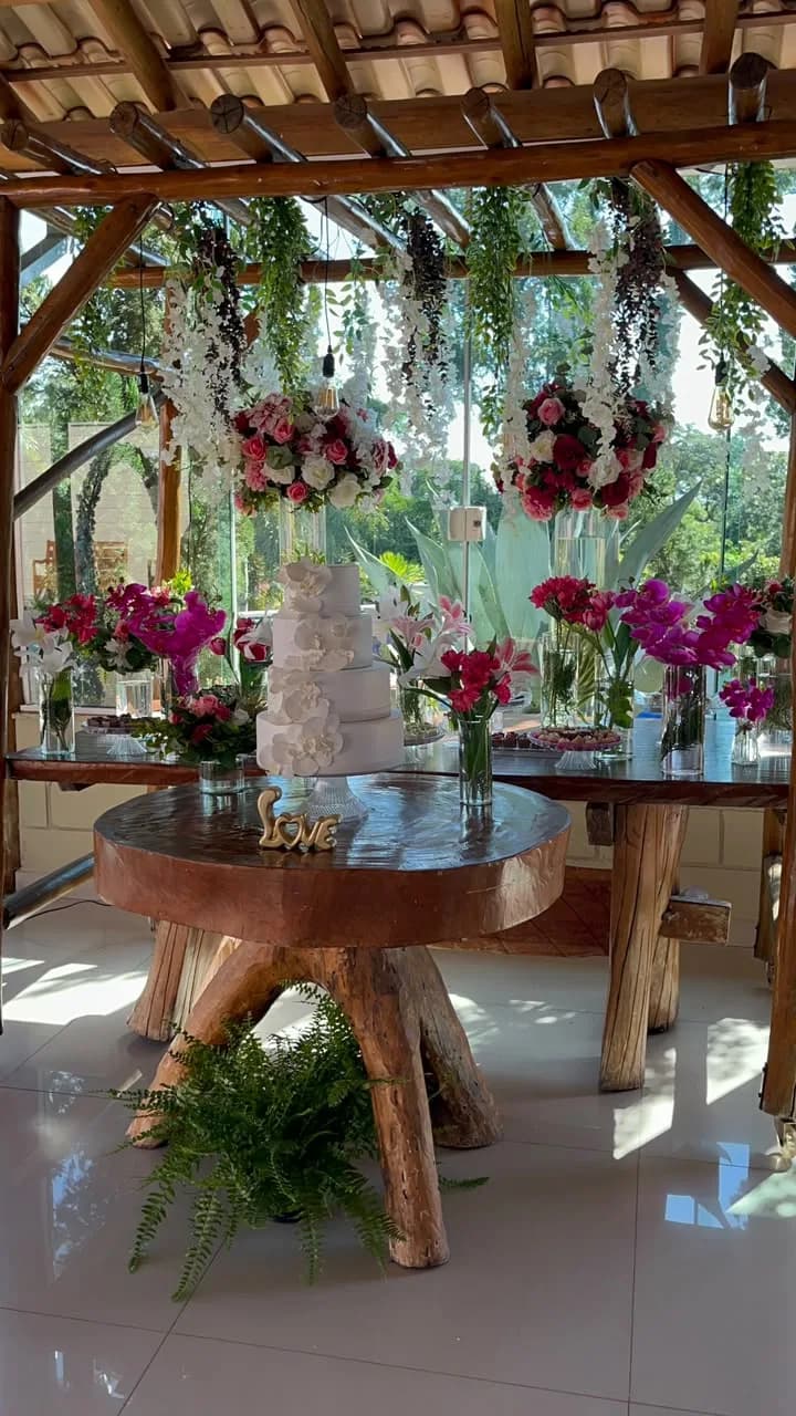 Mesa de bolo com orquídeas e flores fúcsia sob o pergolado